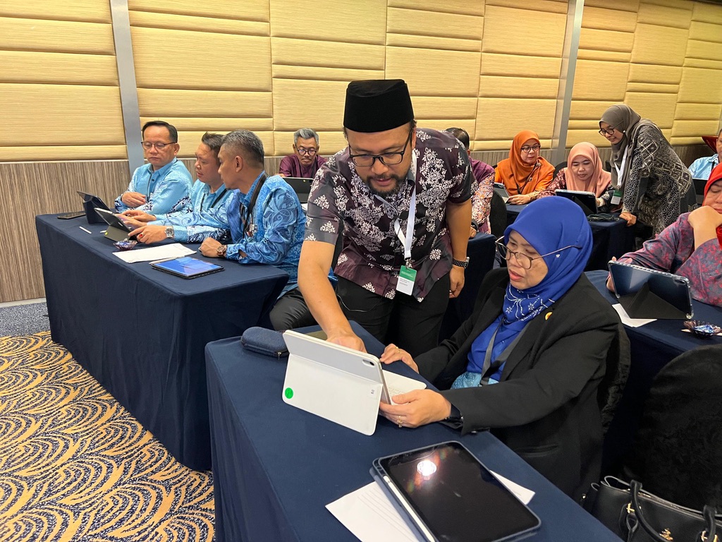 Guiding a participant on an iPad at the Institut Aminuddin Baki symposium